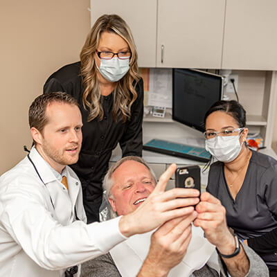 New Patients Dental-Care-of-Sumner-with-patient-holding-phone-for-selfie